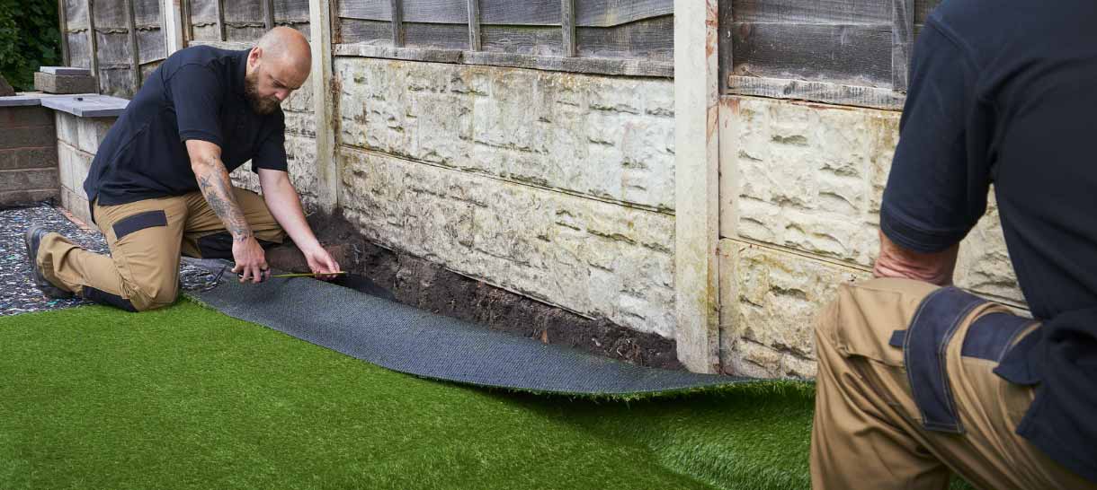 Two men installing artificial turf with water-based adhesive